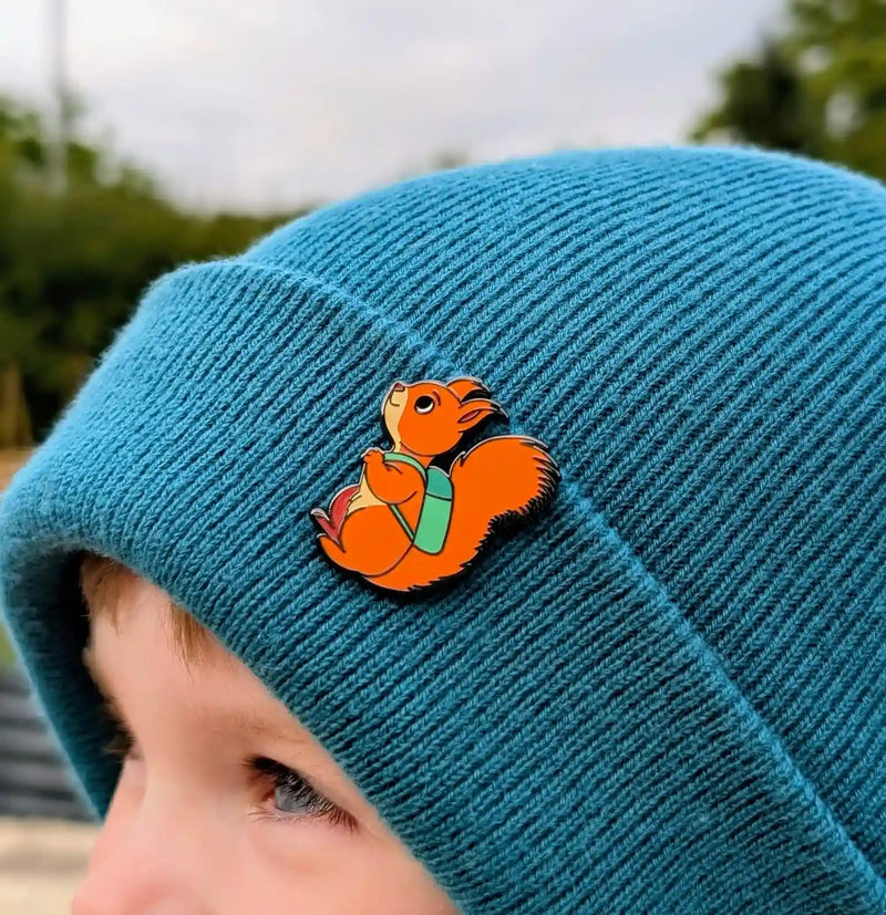 Boy wearing a teal beanie with a red squirrel enamel pin badge