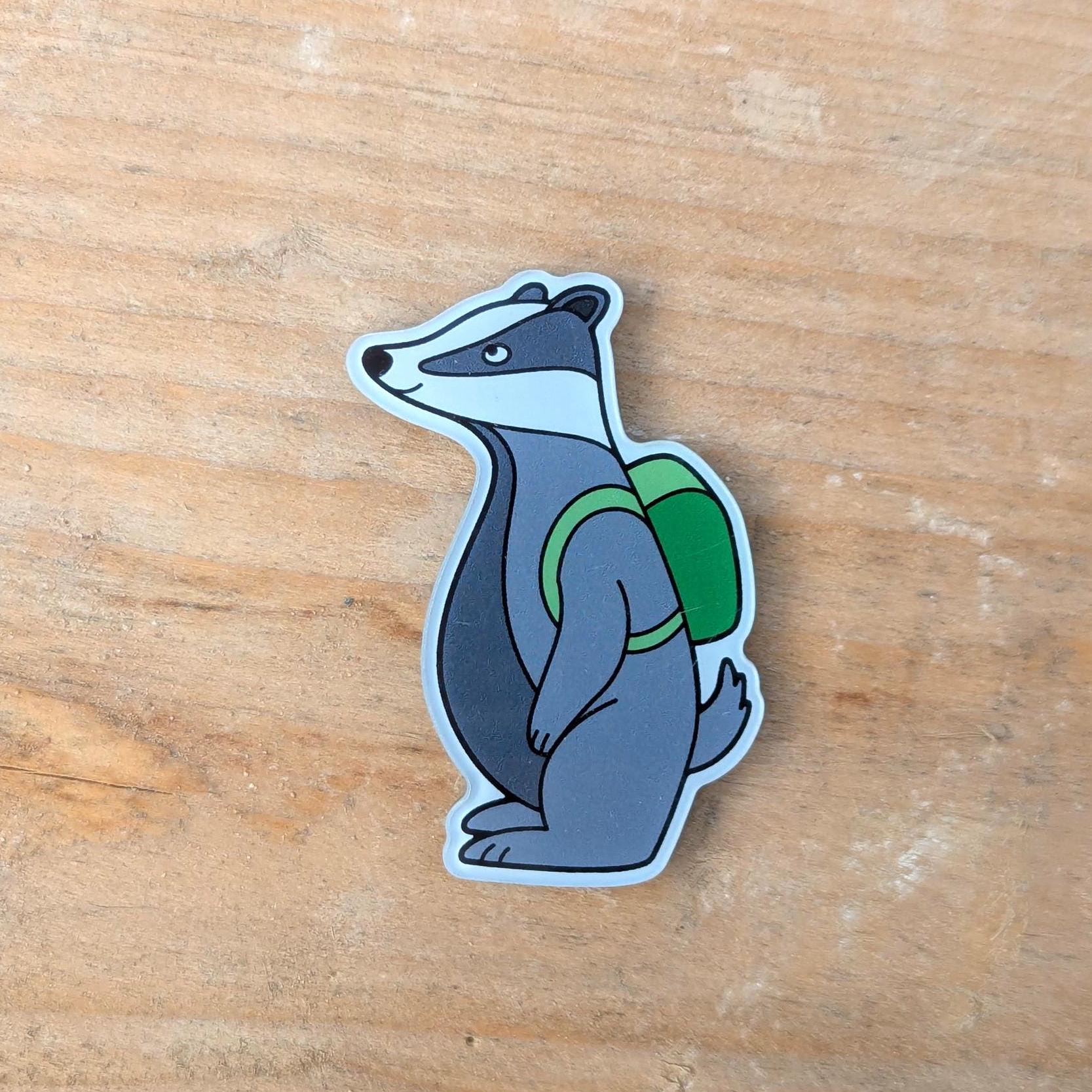 Badger Magnet with a green backpack on a wooden surface