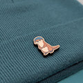 Wooden pin of a cartoon otter on a textured teal fabric background