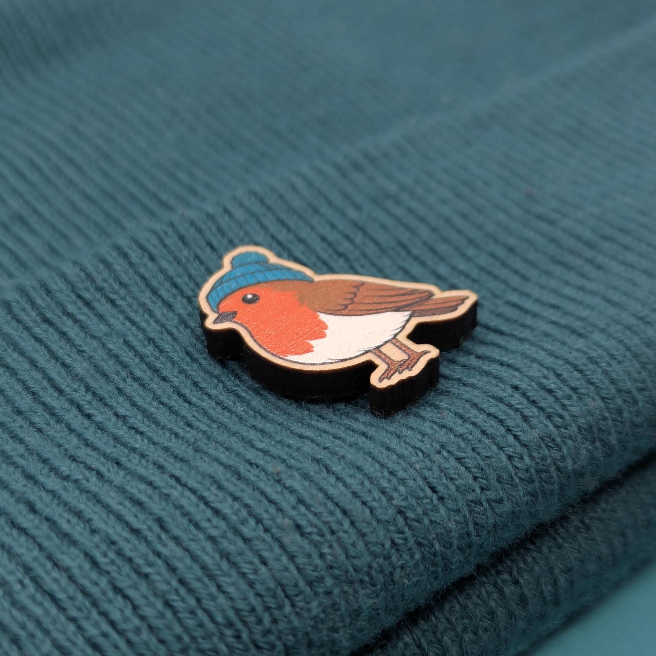 Robin wooden pin badge on a textured teal fabric background