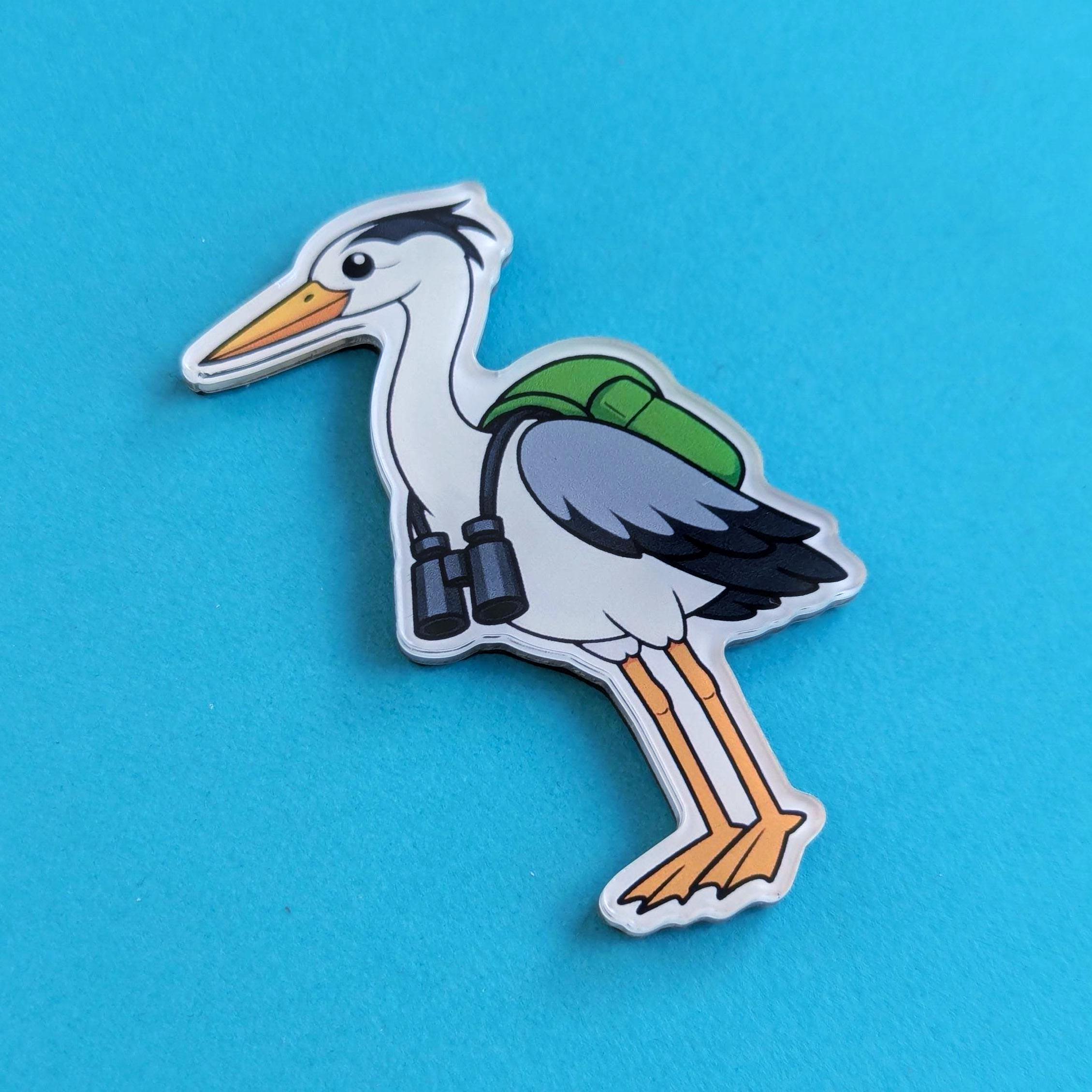 Acrylic fridge magnet of a heron with a backpack and binoculars on a blue background