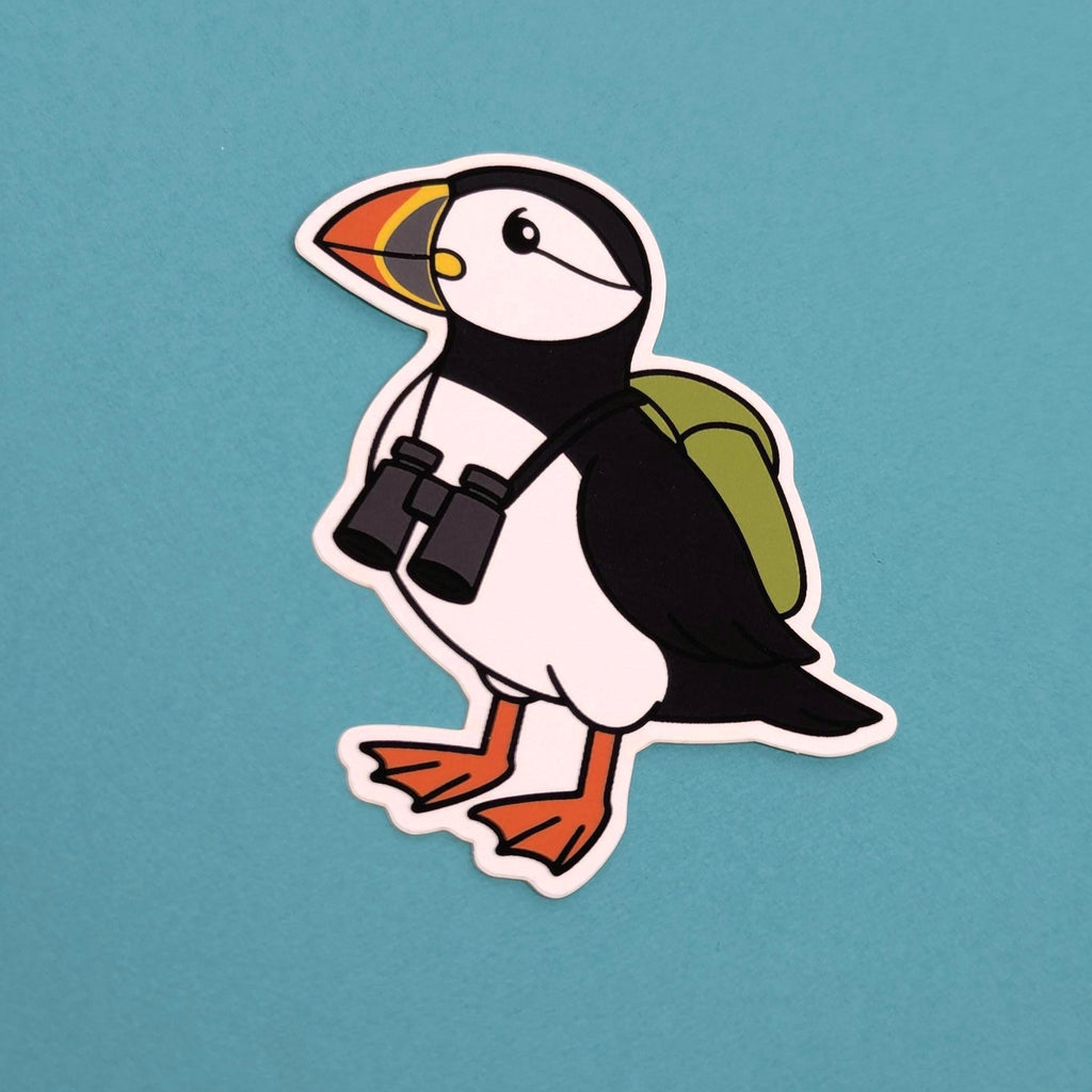 Sticker of a puffin with binoculars and a backpack on a blue background