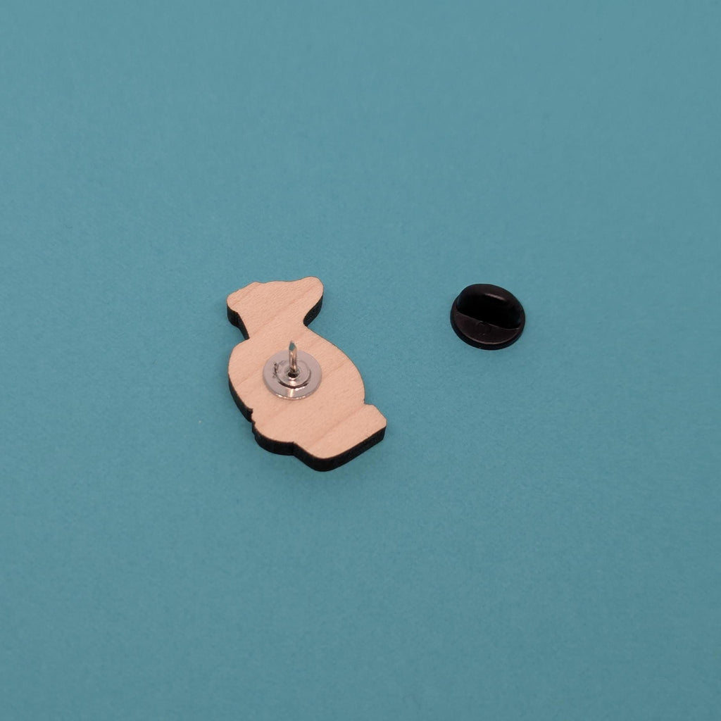 badger wooden pin back with a black ball on a teal background