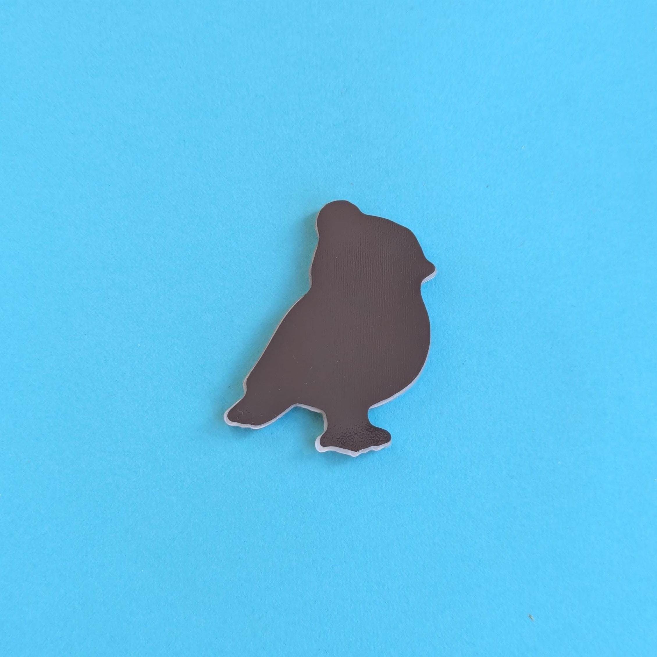 Back view of a robin in a beanie hat fridge magnet on a blue background