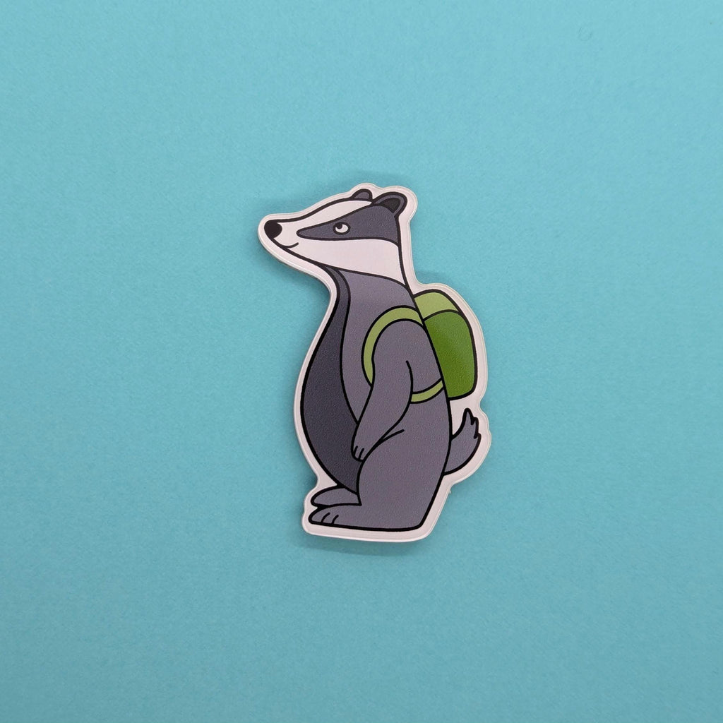 badger fridge magnet with a green backpack on a blue background