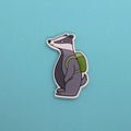 badger fridge magnet with a green backpack on a blue background