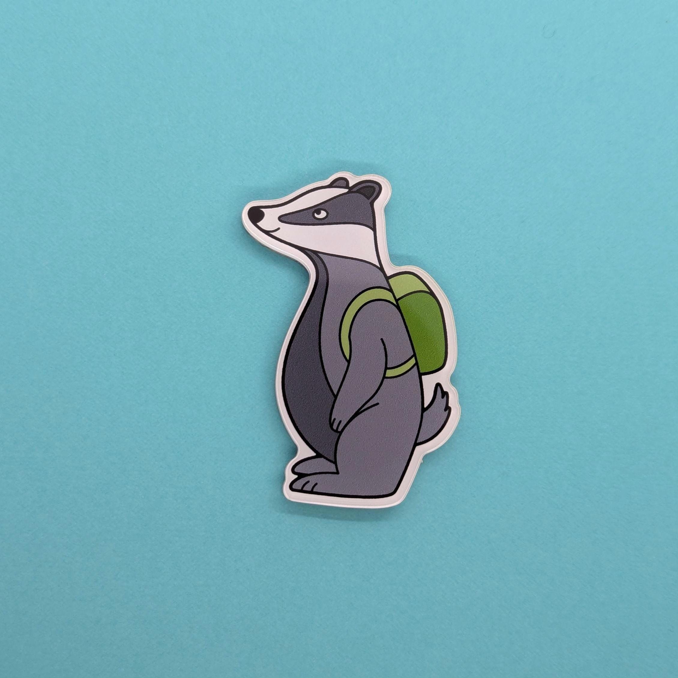 badger fridge magnet with a green backpack on a blue background