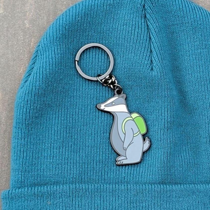 Keychain with a badger design on a blue knit beanie.