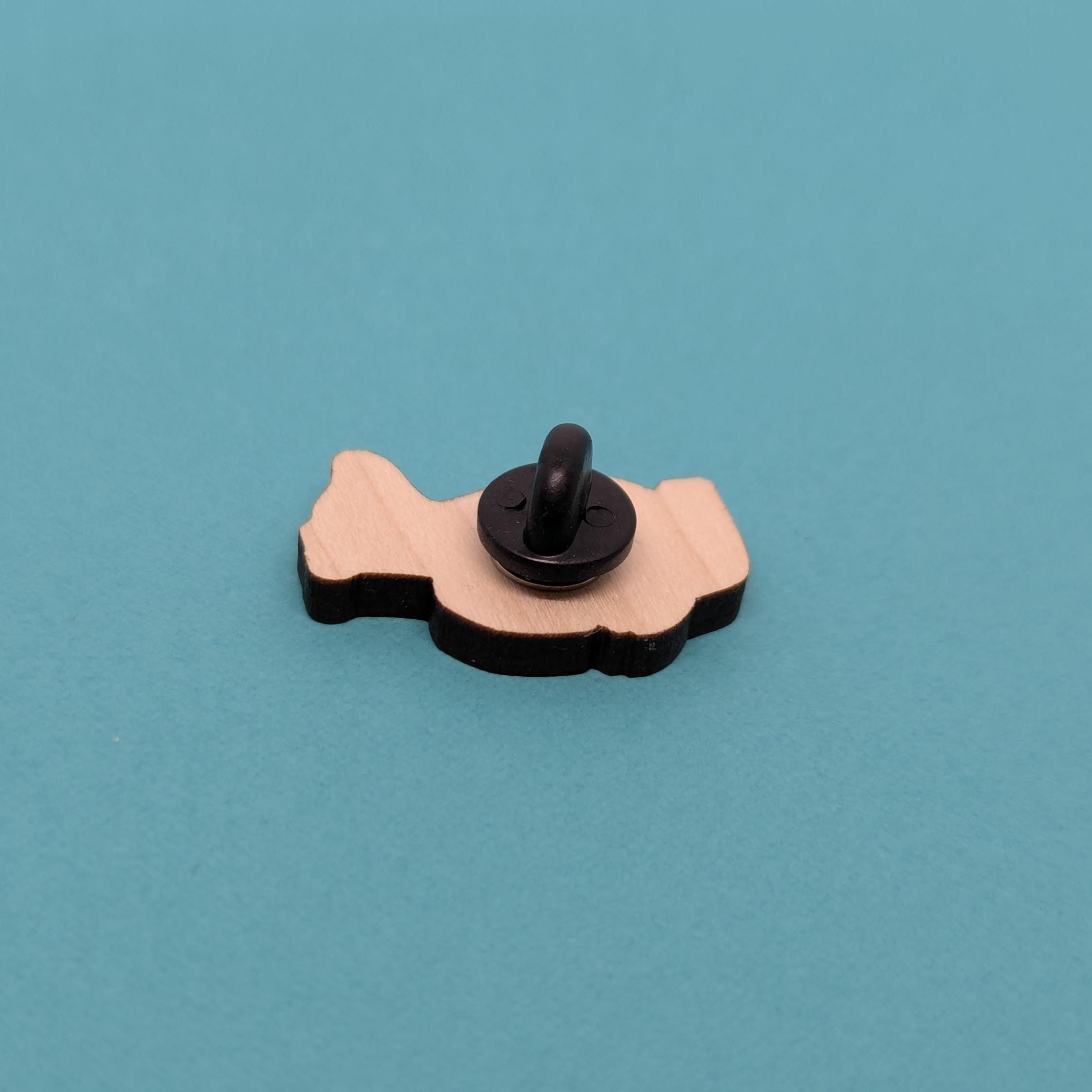 Back of wooden badger pin badge on a blue background