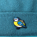 Blue tit pin on a blue textured fabric background