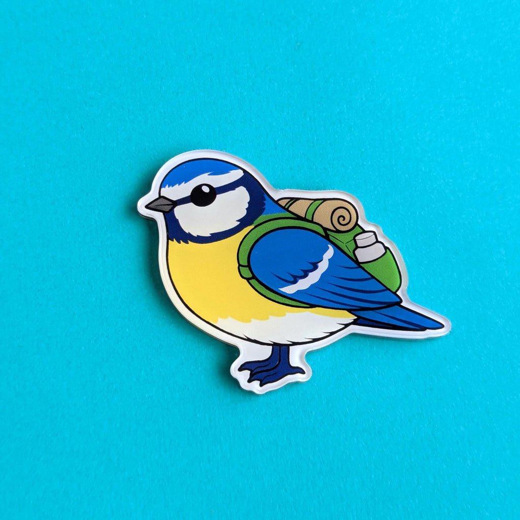 Fridge magnet of a blue and yellow bird holding a roll of tape on a blue background