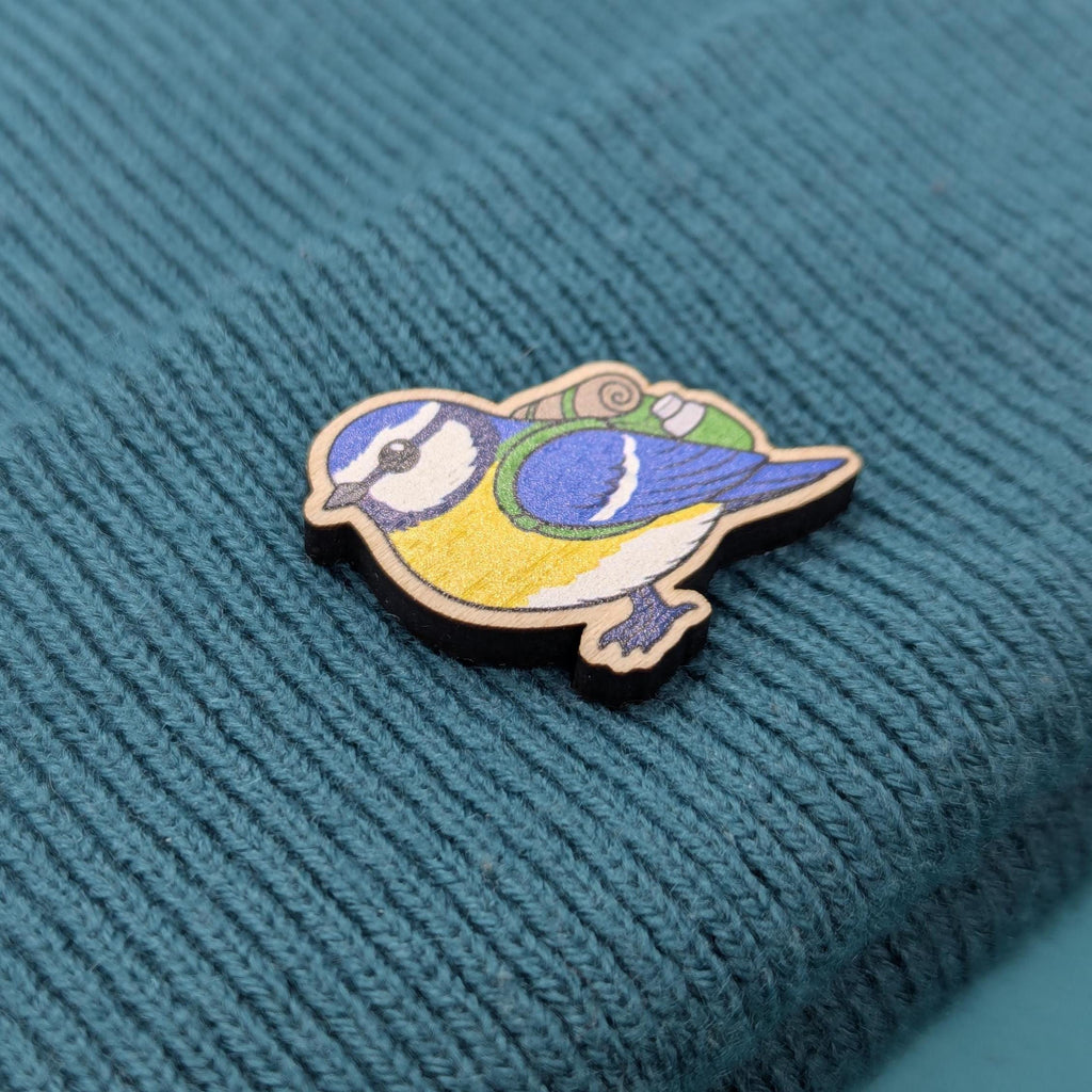 Blue tit wooden pin on a textured teal fabric background