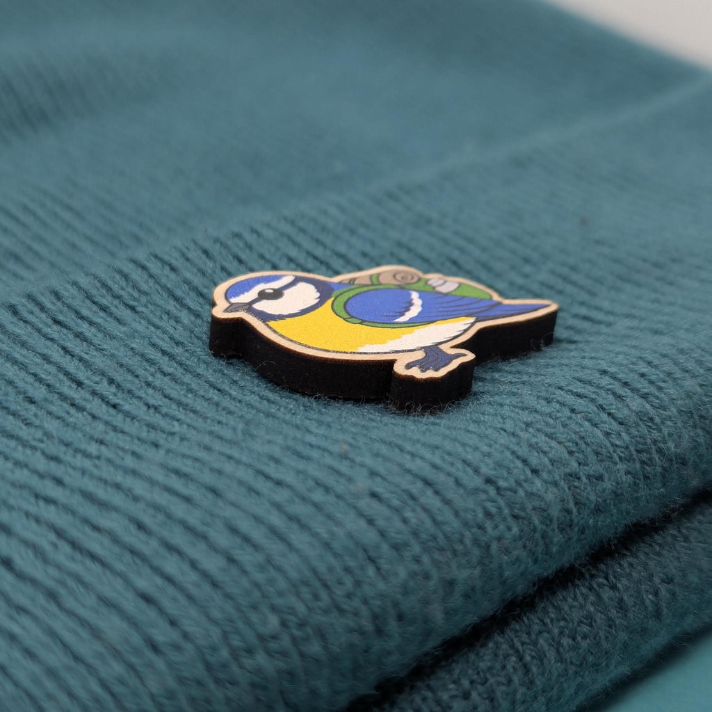 Blue tit wooden pin on a textured teal fabric background