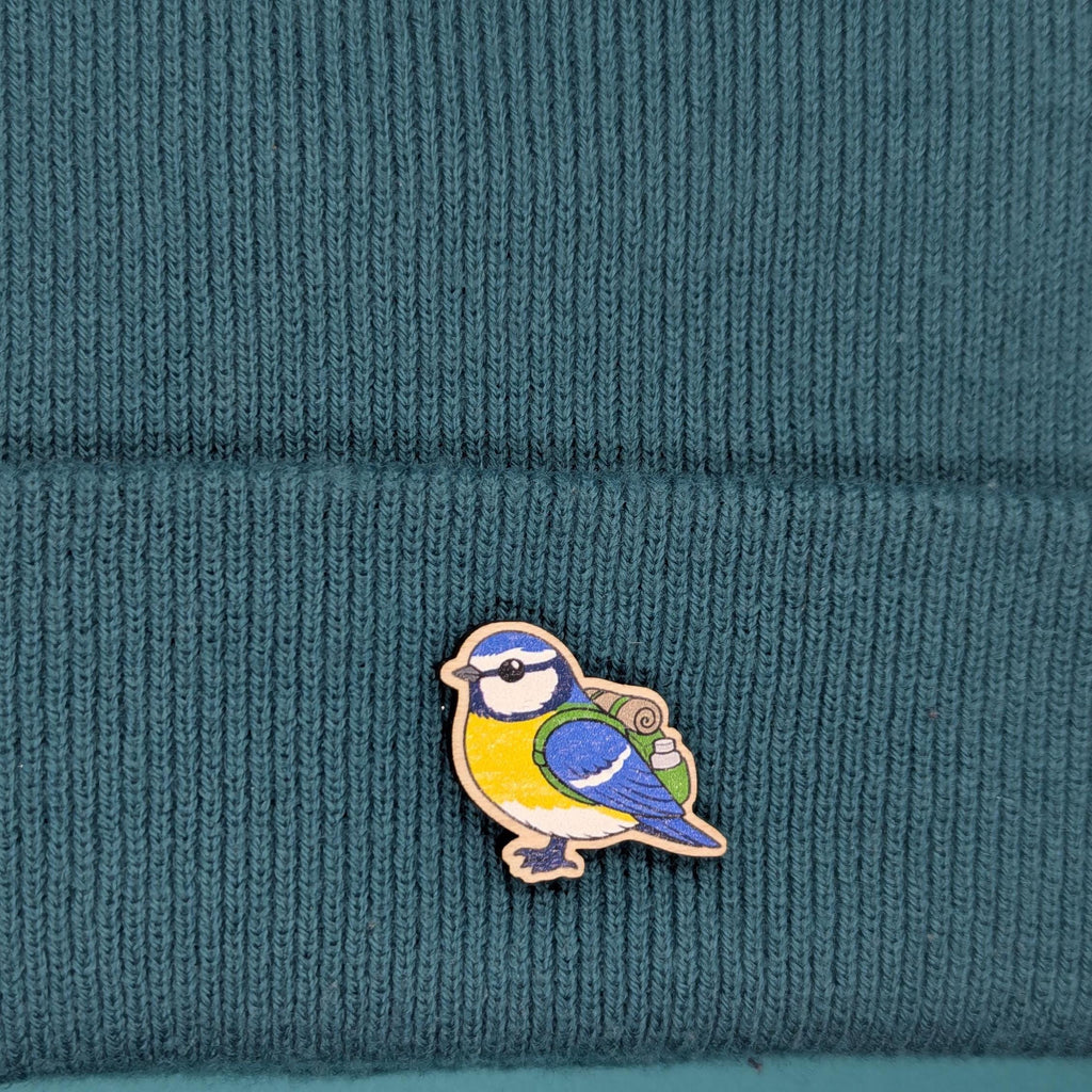 Blue tit wooden pin on a teal knitted fabric