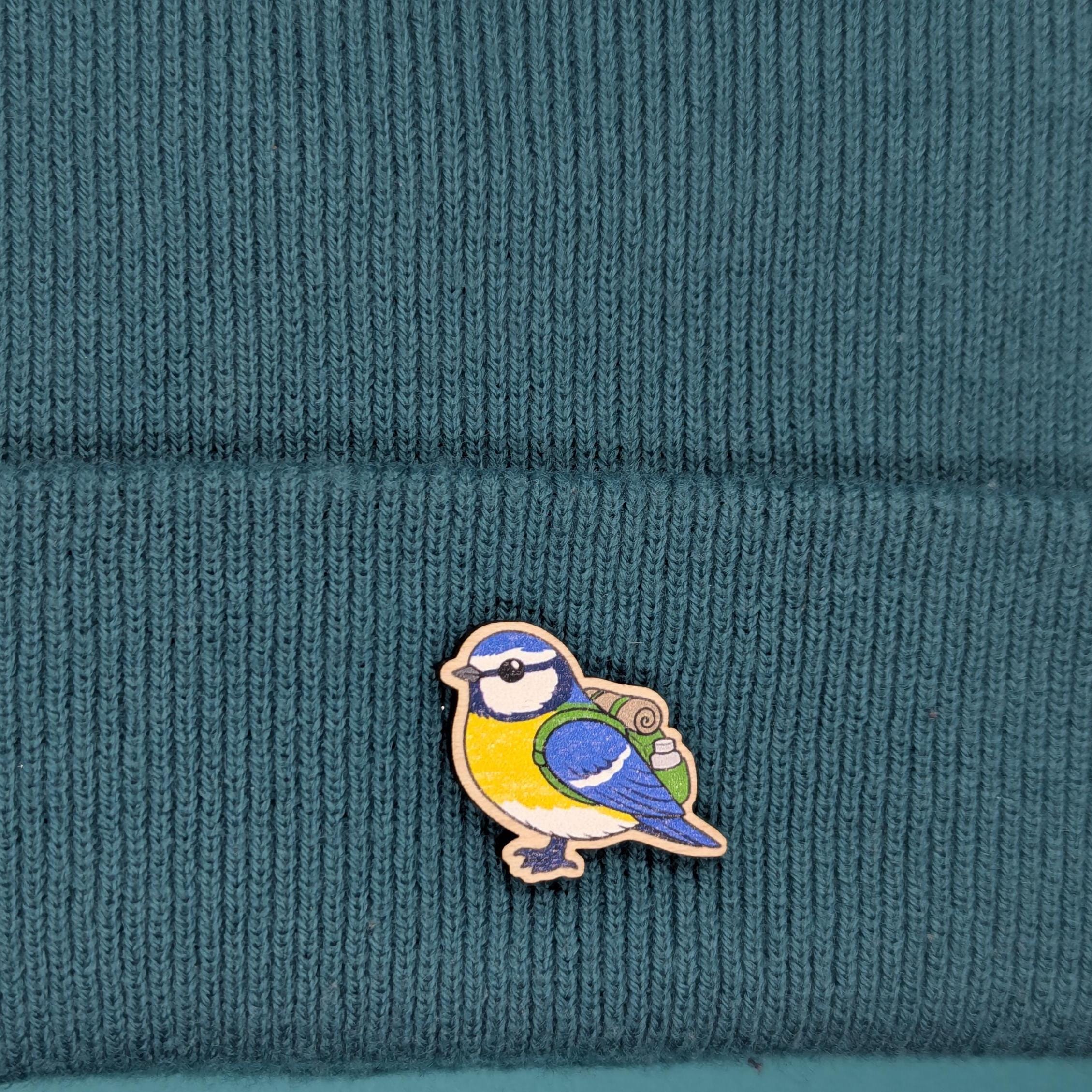 Blue tit wooden pin on a teal knitted fabric
