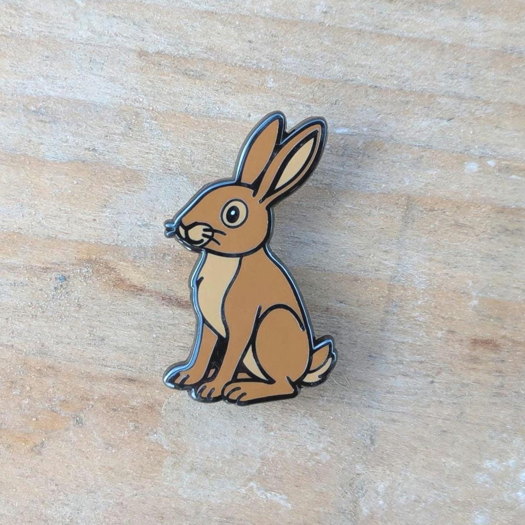 Brown rabbit-shaped pin on a wooden surface