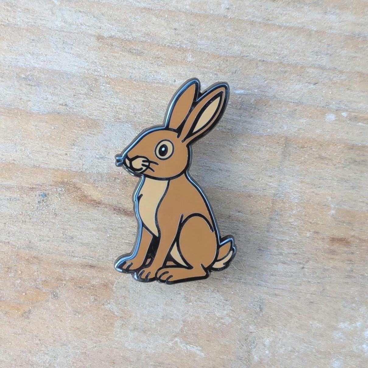Brown rabbit-shaped pin on a wooden surface