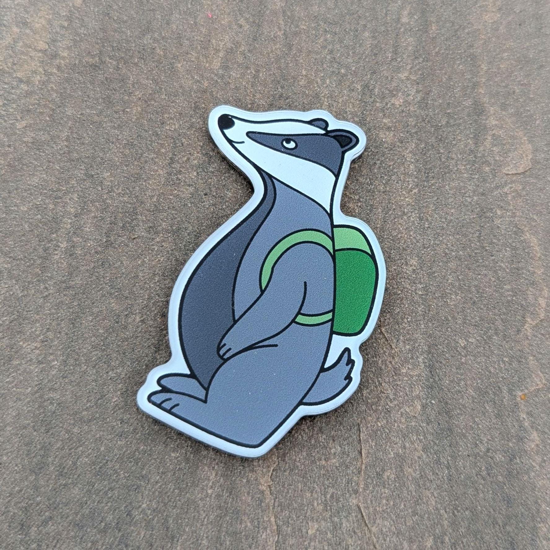 Acrylic badger magnet with a green backpack on a brown surface