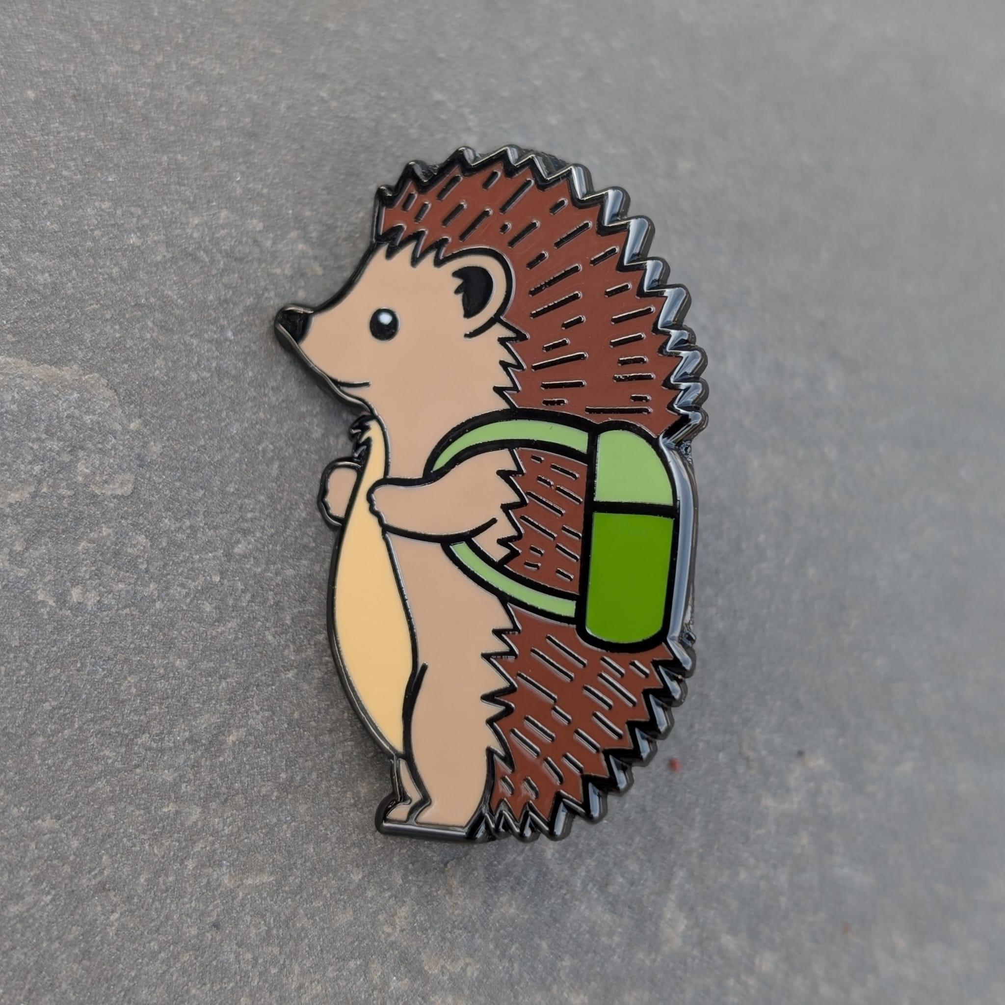 Hedgehog enamel pin with a green backpack on a gray background