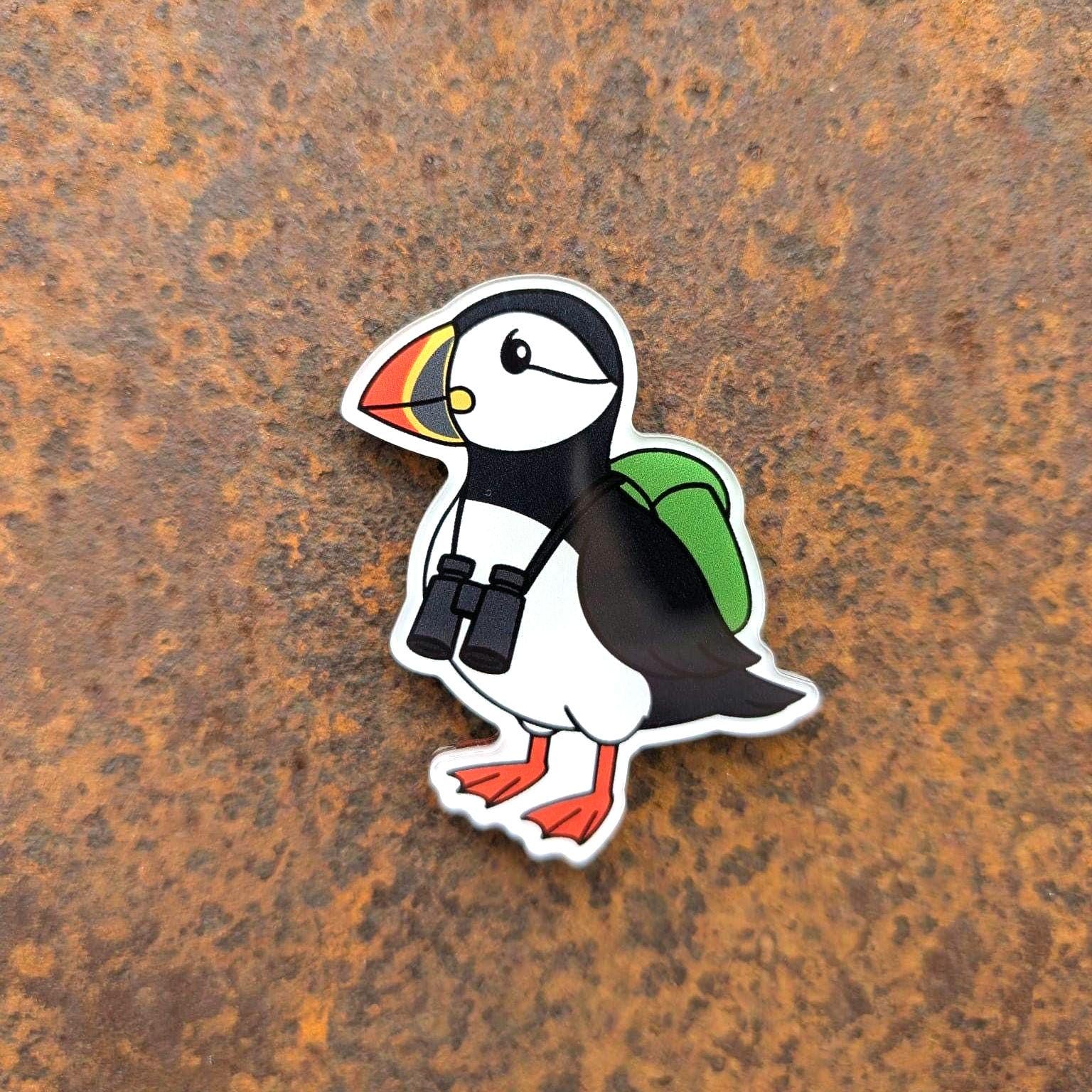 Puffin fridge magnet with a backpack and binoculars on a rusty metal background