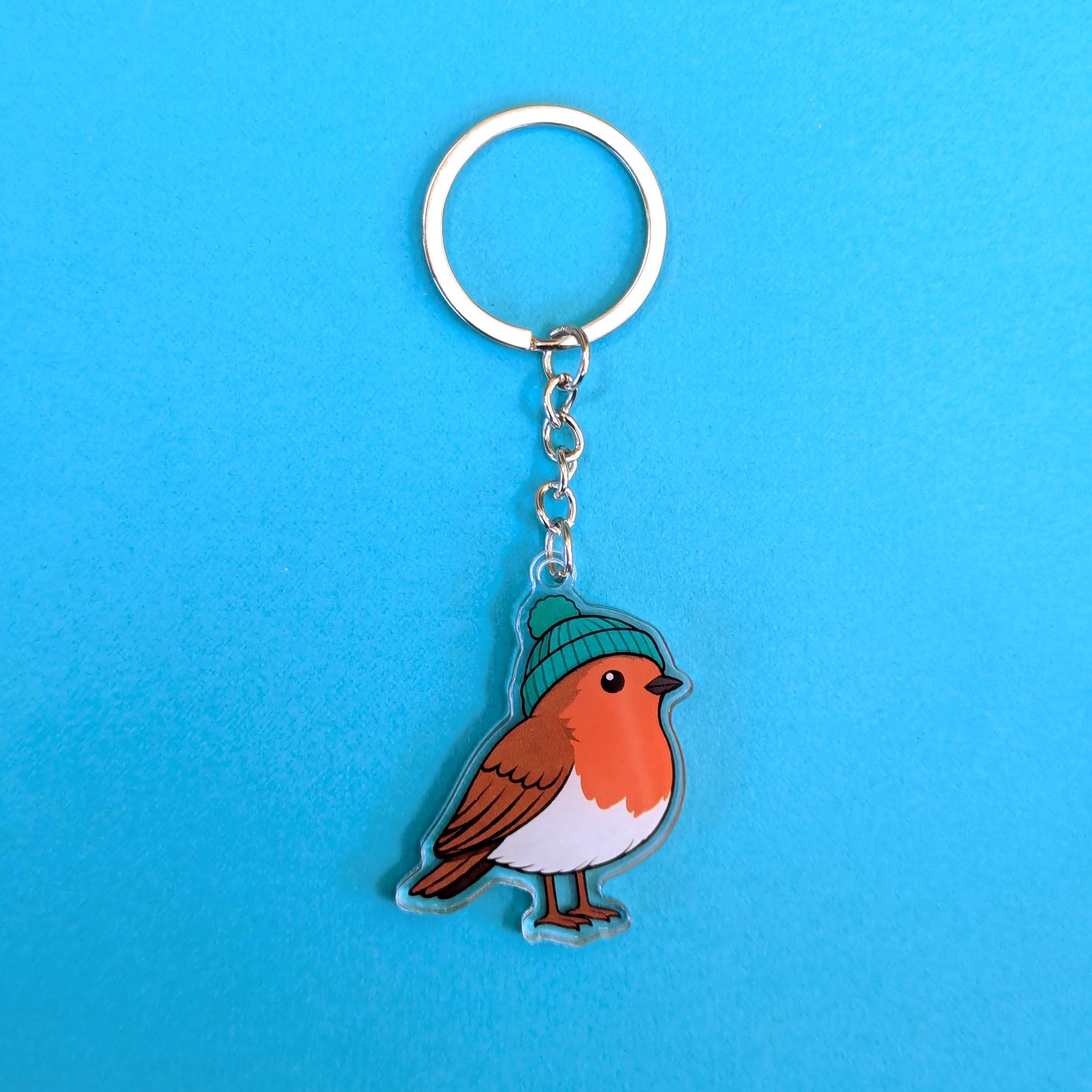 Keychain with a robin design wearing a green beanie on a blue background
