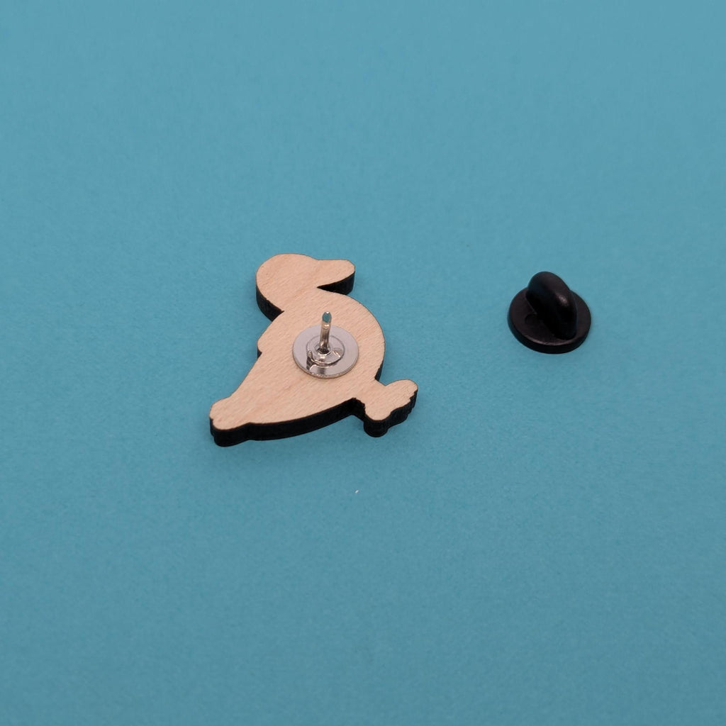 Wooden duck pin back with a black clutch on a blue background