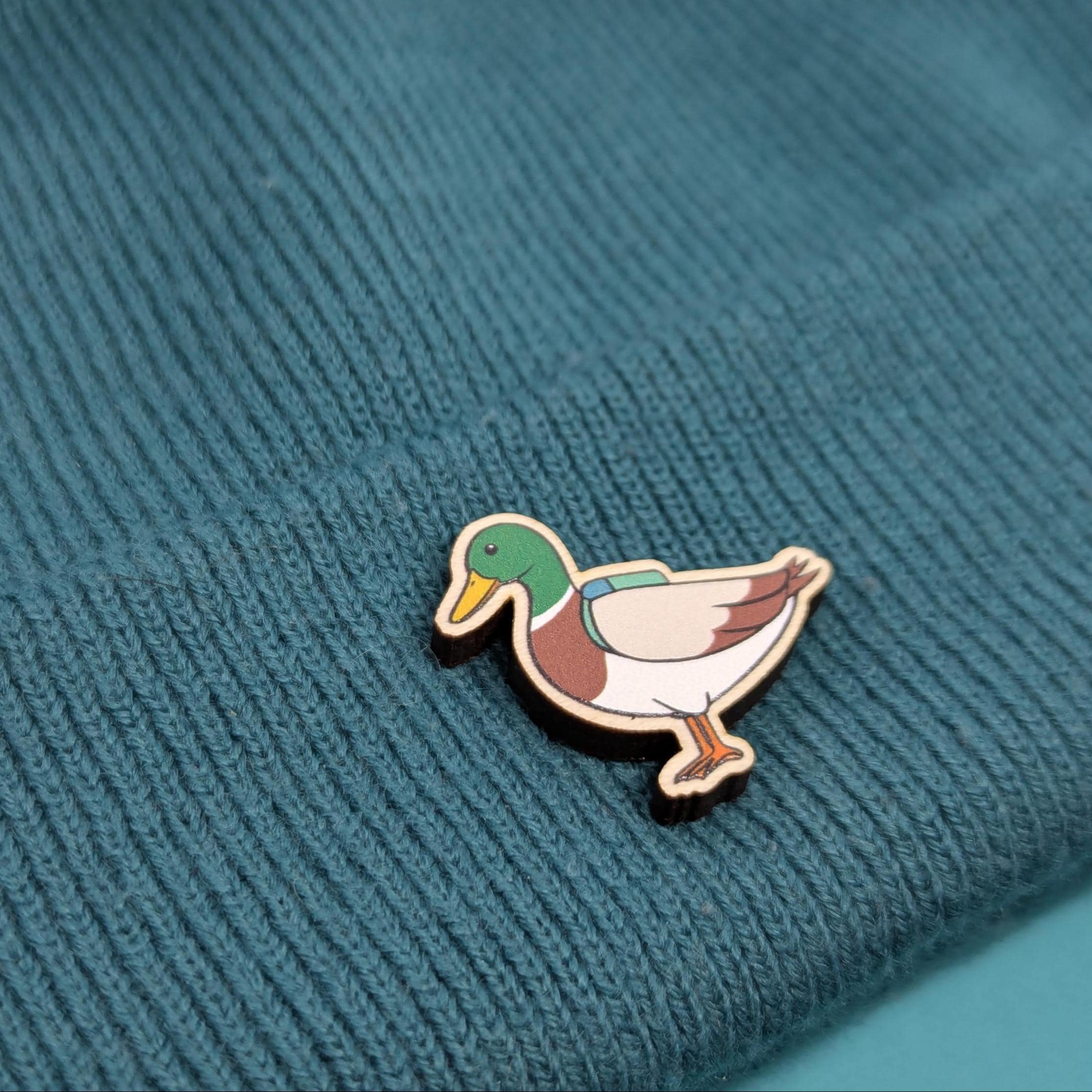 Duck wooden pin on a textured teal fabric background