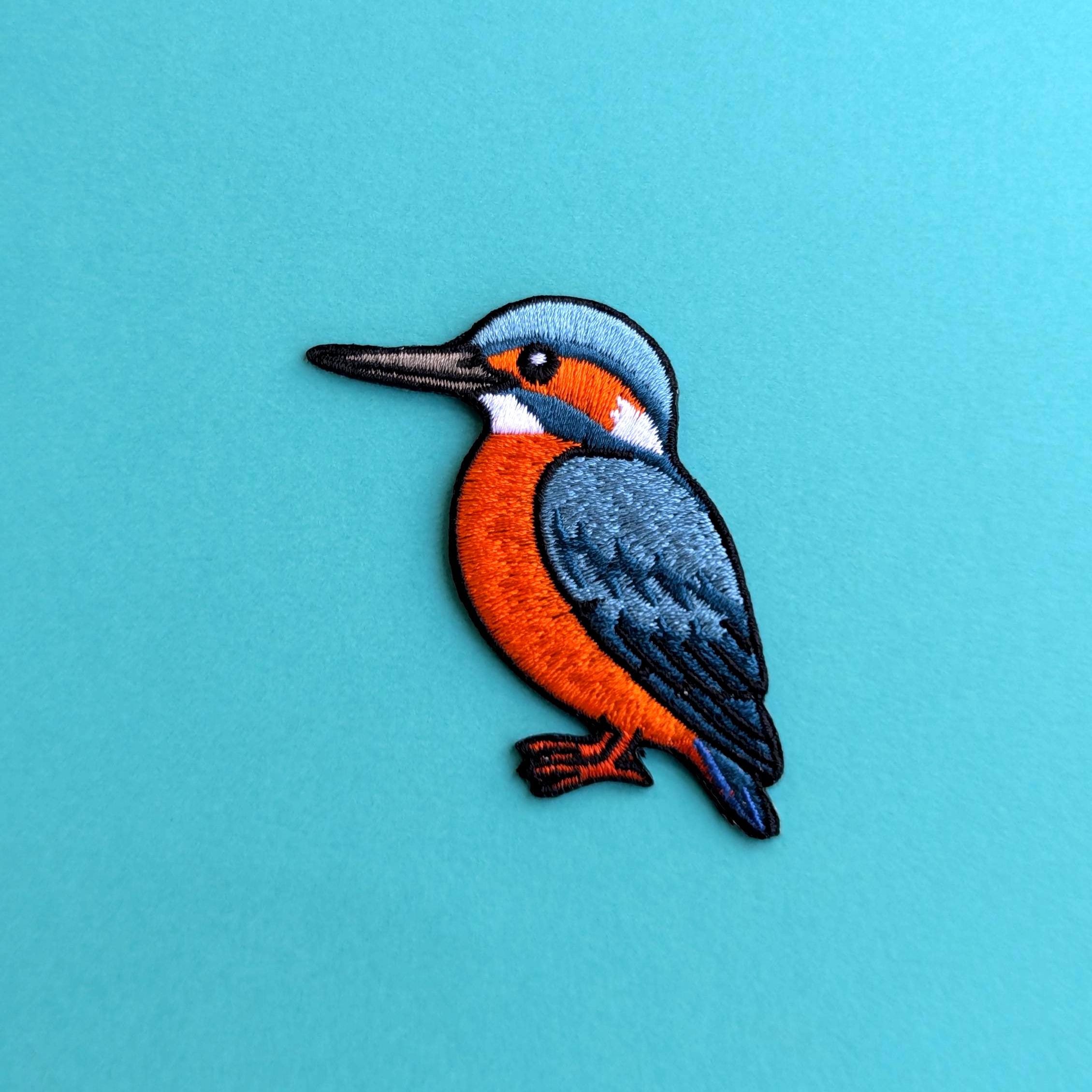 Embroidered patch of a kingfisher bird on a blue background