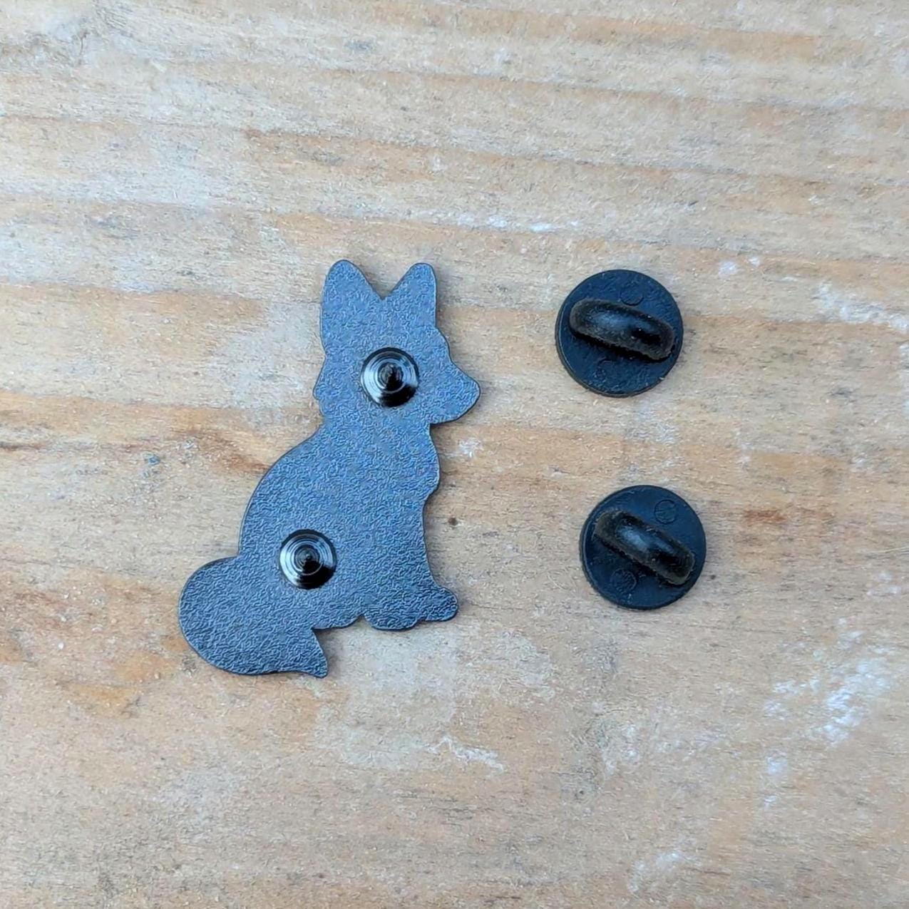back of fox pin with black metal components on a wooden surface