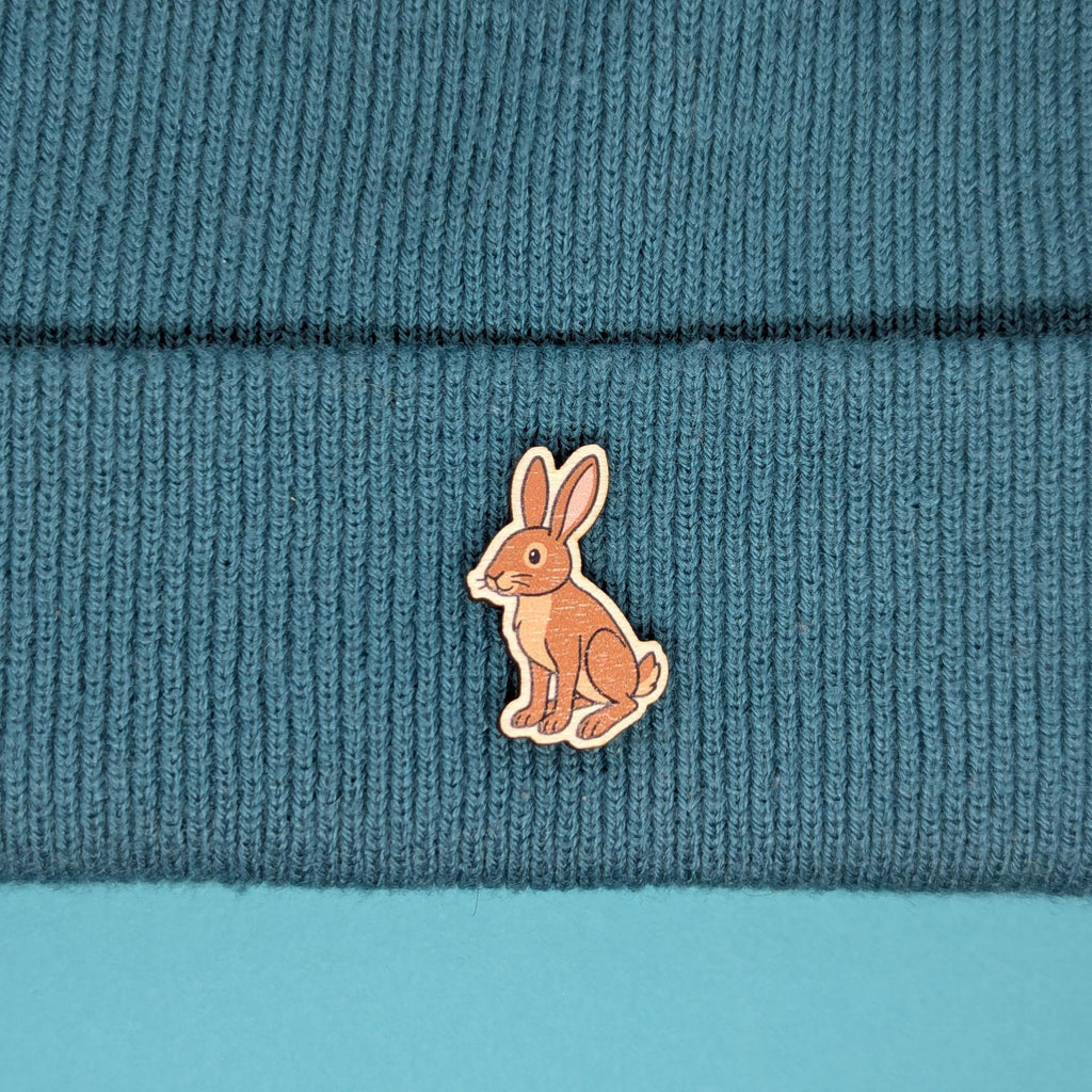hare wooden pin badge on a beanie