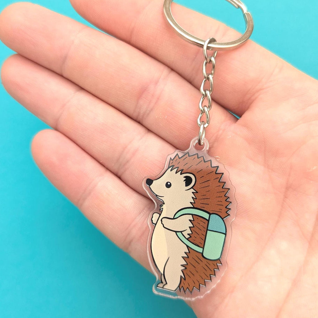 Hedgehog keychain held in a hand against a blue background