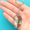 Hedgehog keychain held in a hand against a blue background