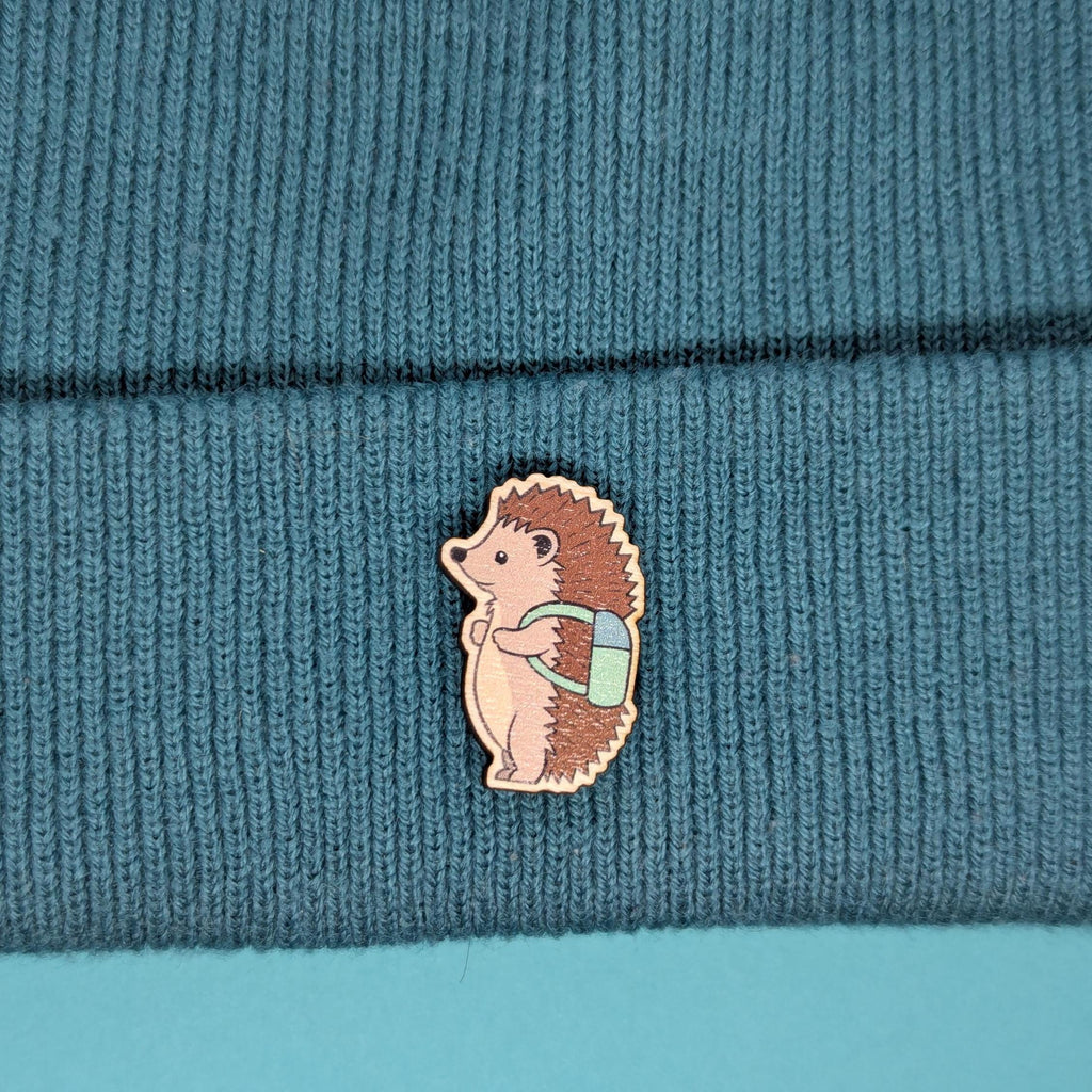 Hedgehog wooden pin on a teal knitted fabric background