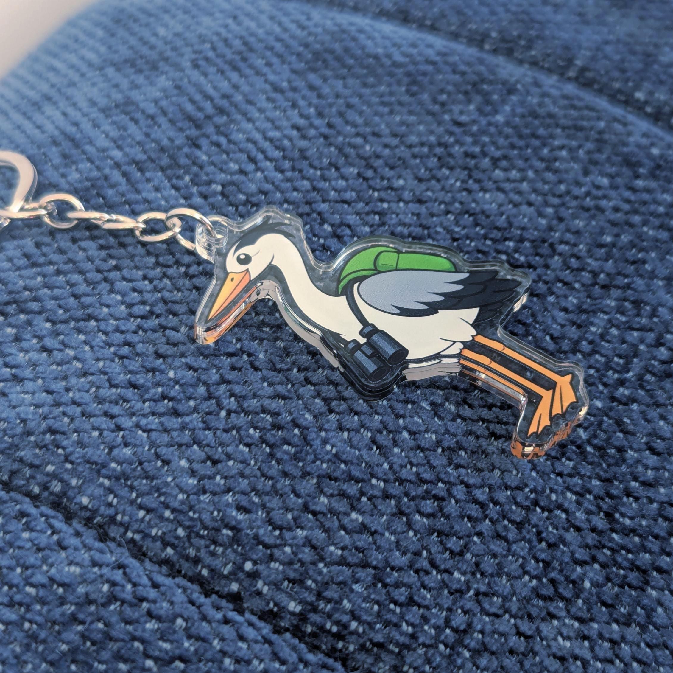 Keychain with a heron bird design on a blue textured fabric background
