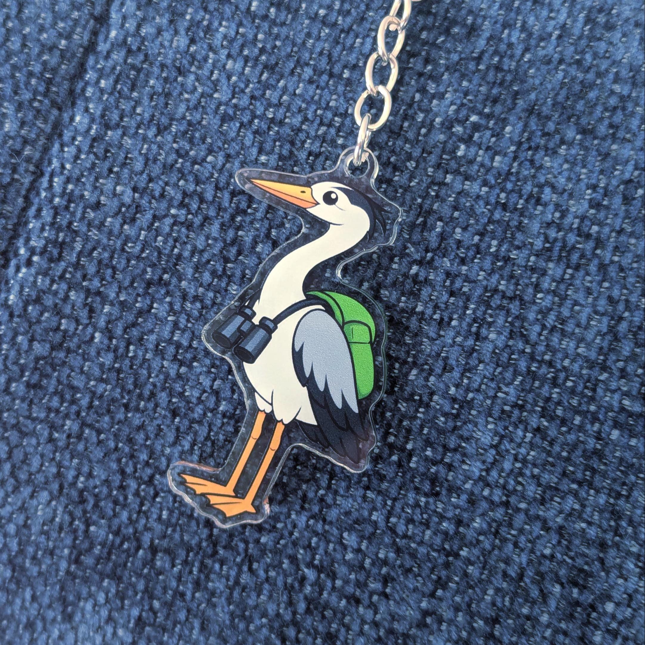 Heron keychain with a backpack on a blue denim background