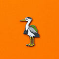 Heron pin with a backpack on an orange background