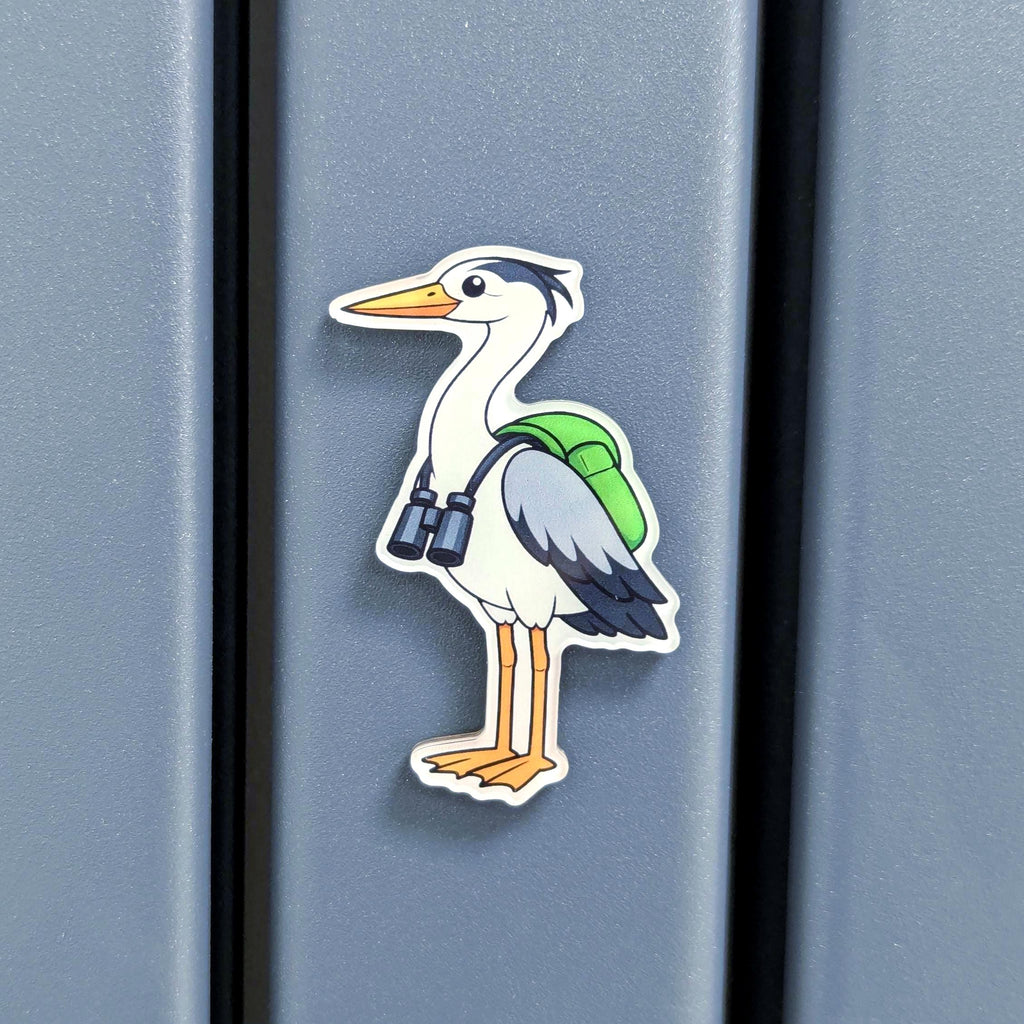 Fridge magnet of a cartoon heron with a green backpack and binoculars on a blue background