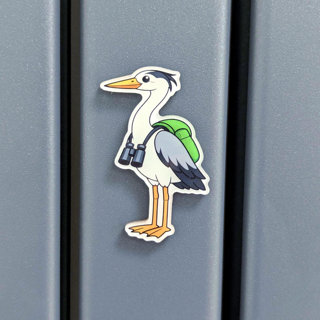 Fridge magnet of a heron with binoculars on a grey surface