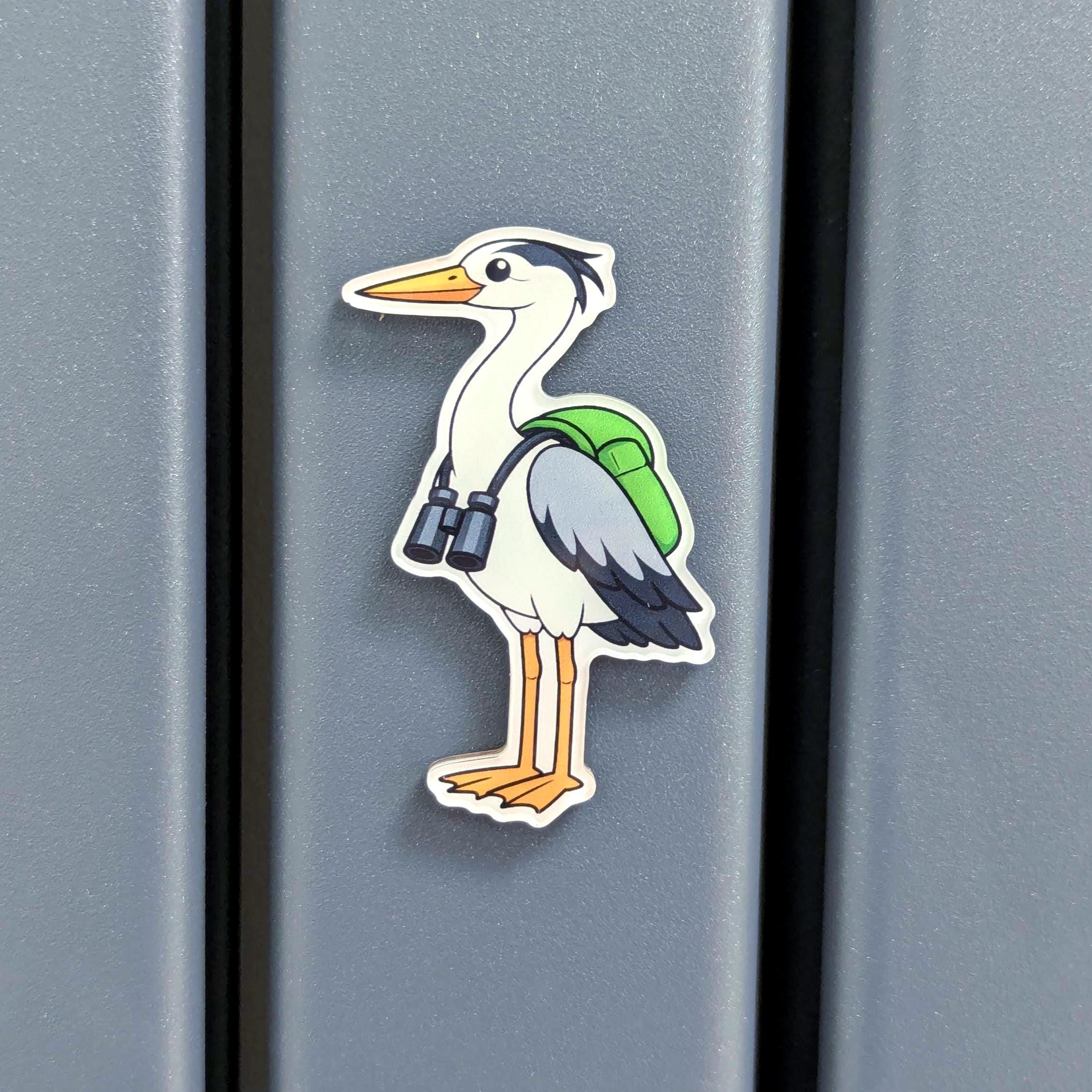 Fridge magnet of a heron with binoculars on a grey surface