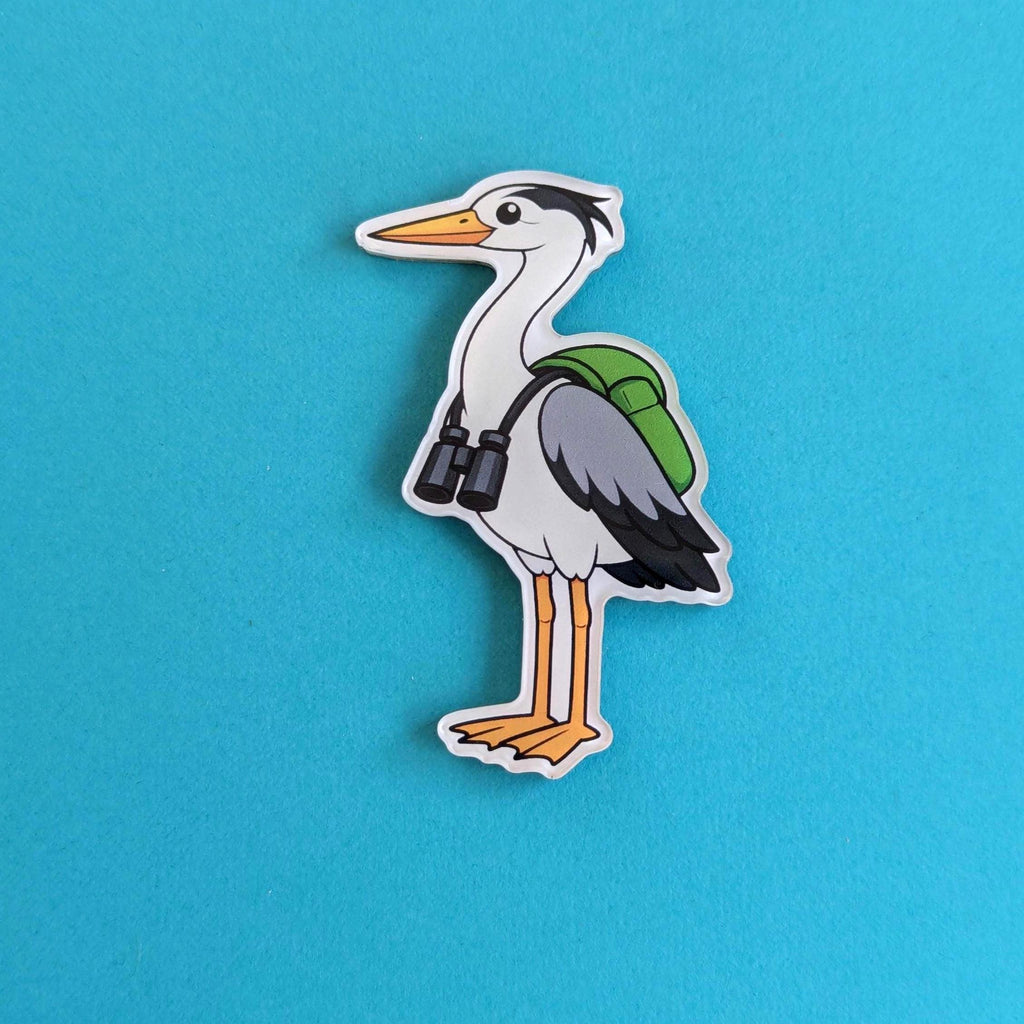 Cartoon heron fridge magnet with a green backpack and binoculars on a blue background