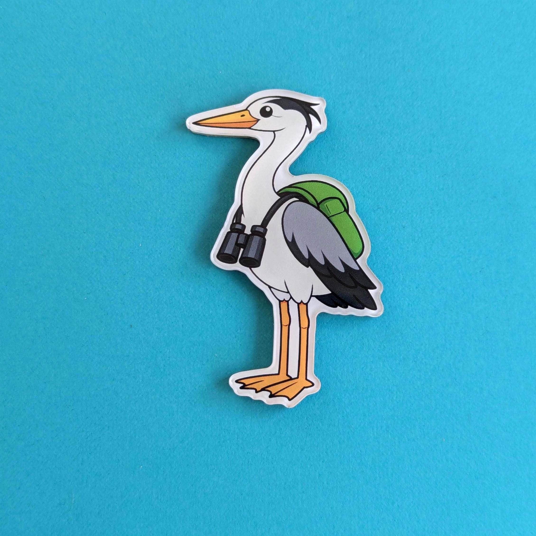Cartoon heron fridge magnet with a green backpack and binoculars on a blue background