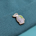 Badger wooden pin with a green backpack on a teal fabric background