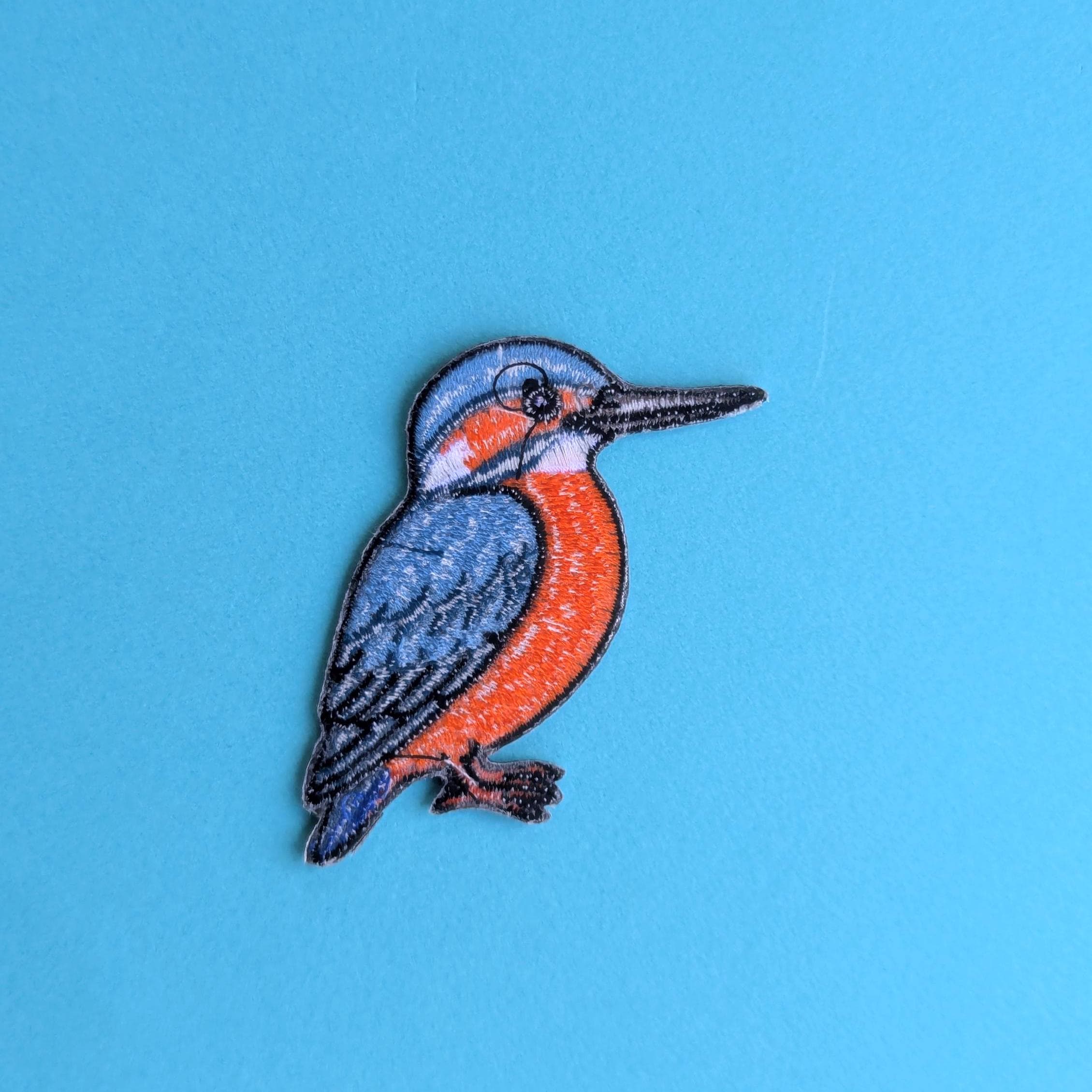 Back view of kingfisher patch with blue and orange colours on a blue background