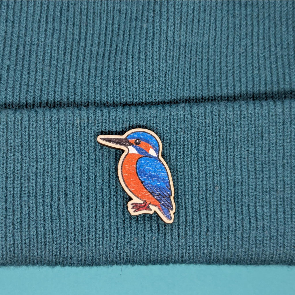 Kingfisher wooden pin on a teal knitted fabric background