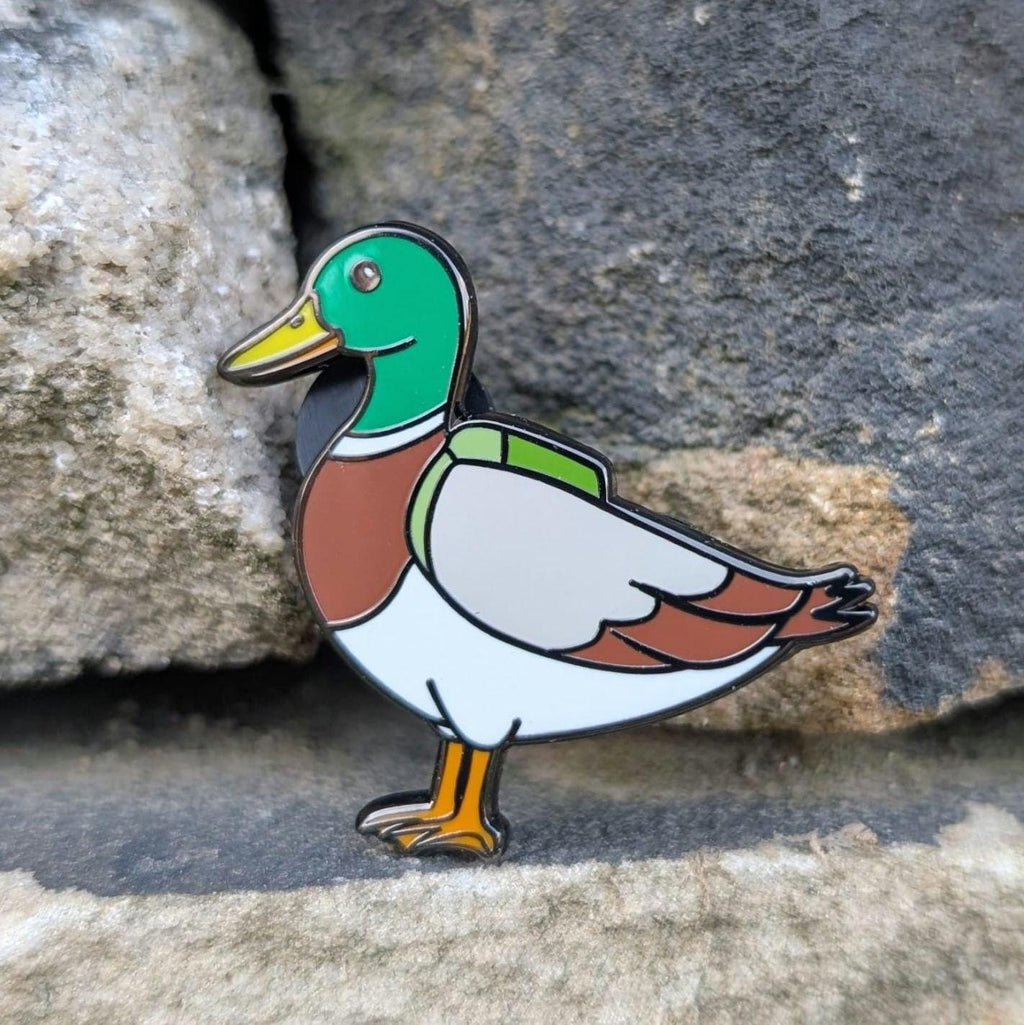 Mallard pin badge on a stone surface