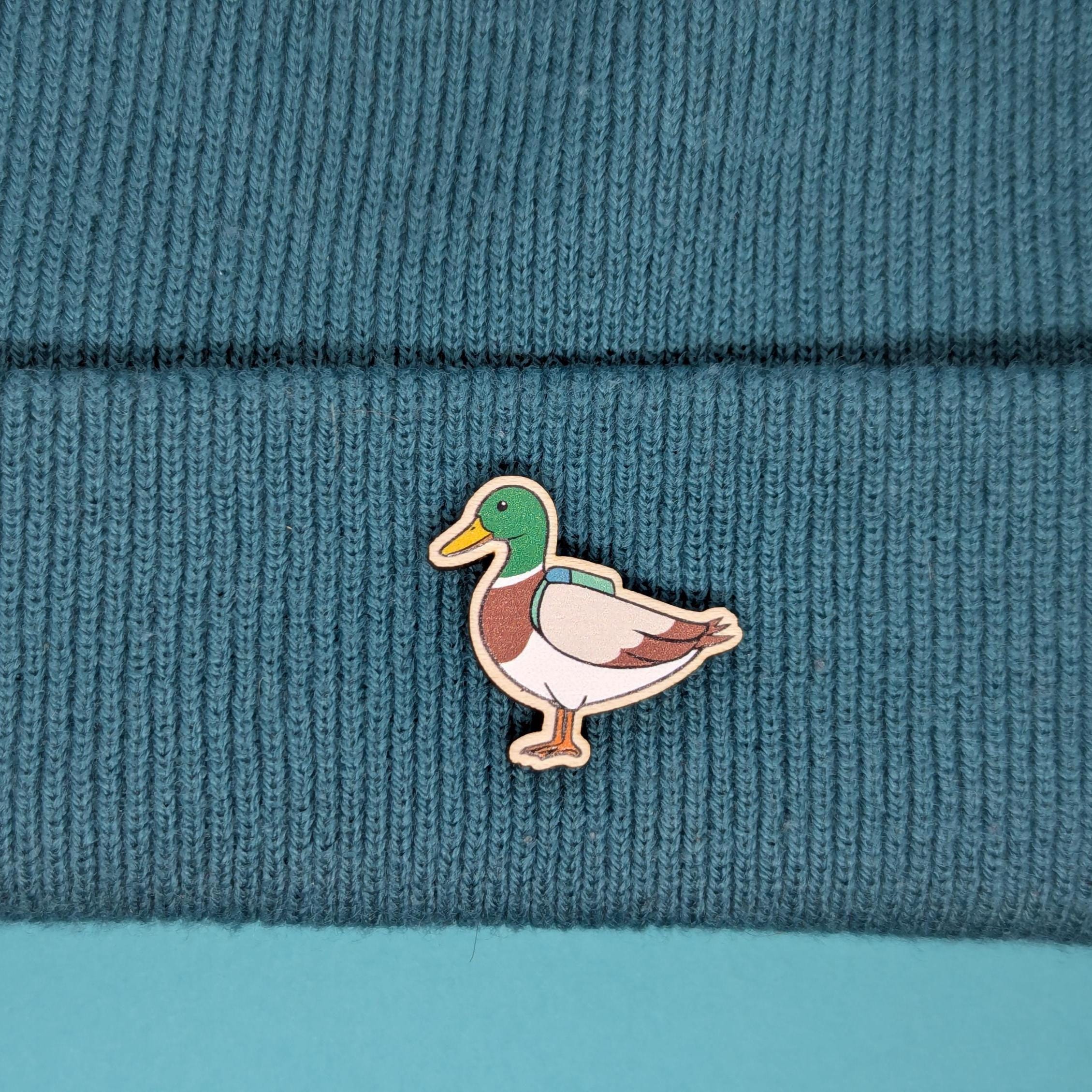 Duck wooden pin on a teal knitted fabric background