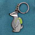 Keychain with a badger design wearing a green backpack on a blue textured background