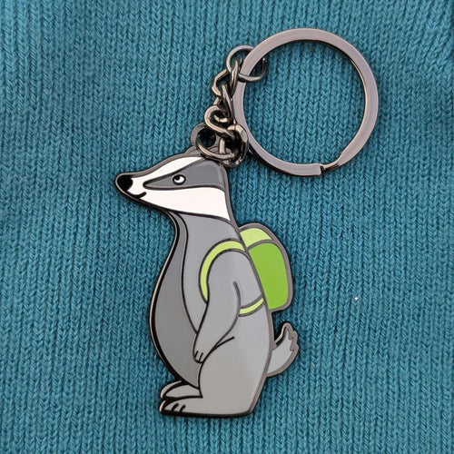 Keychain with a badger design wearing a green backpack on a blue textured background