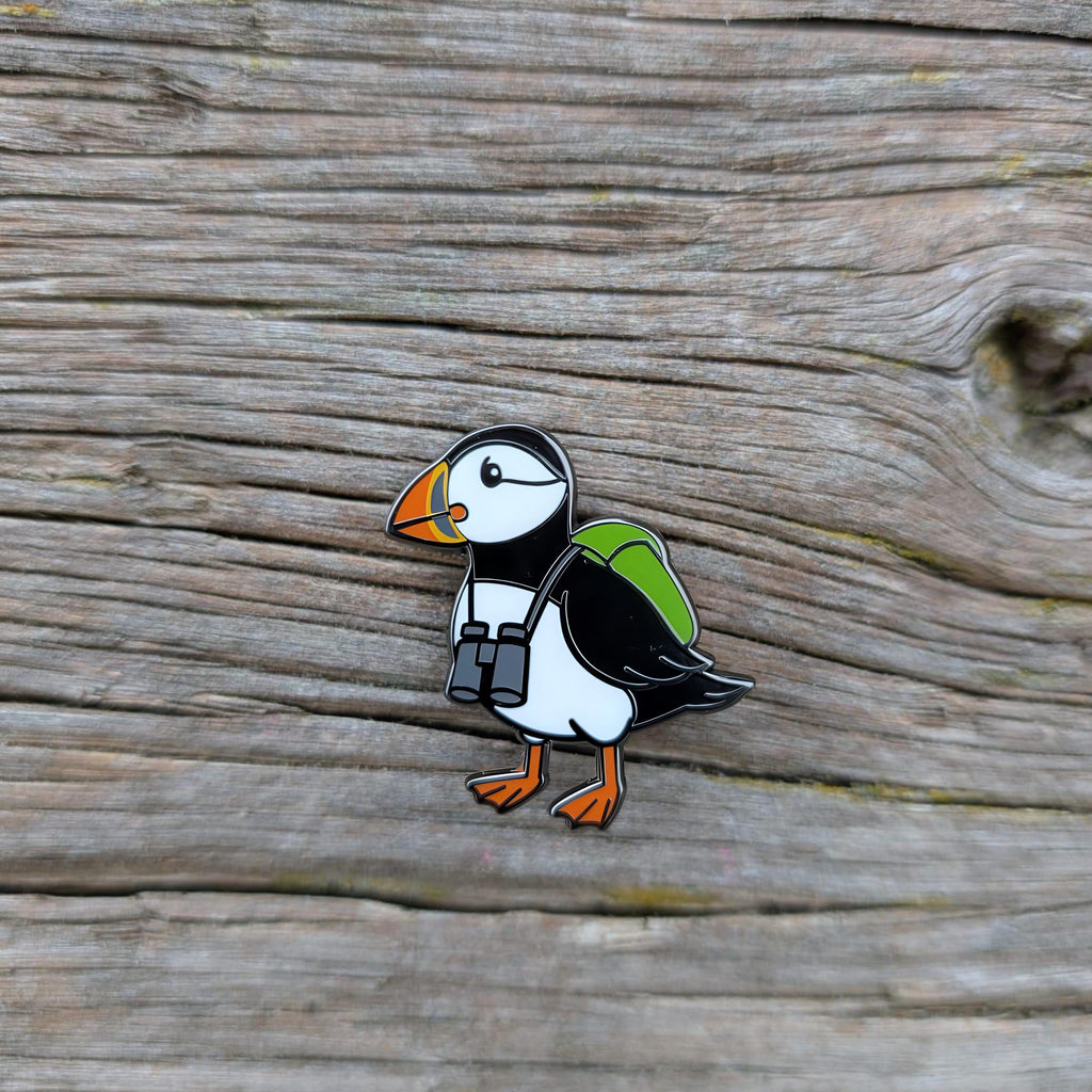 Puffin-shaped pin with a backpack on a wooden surface