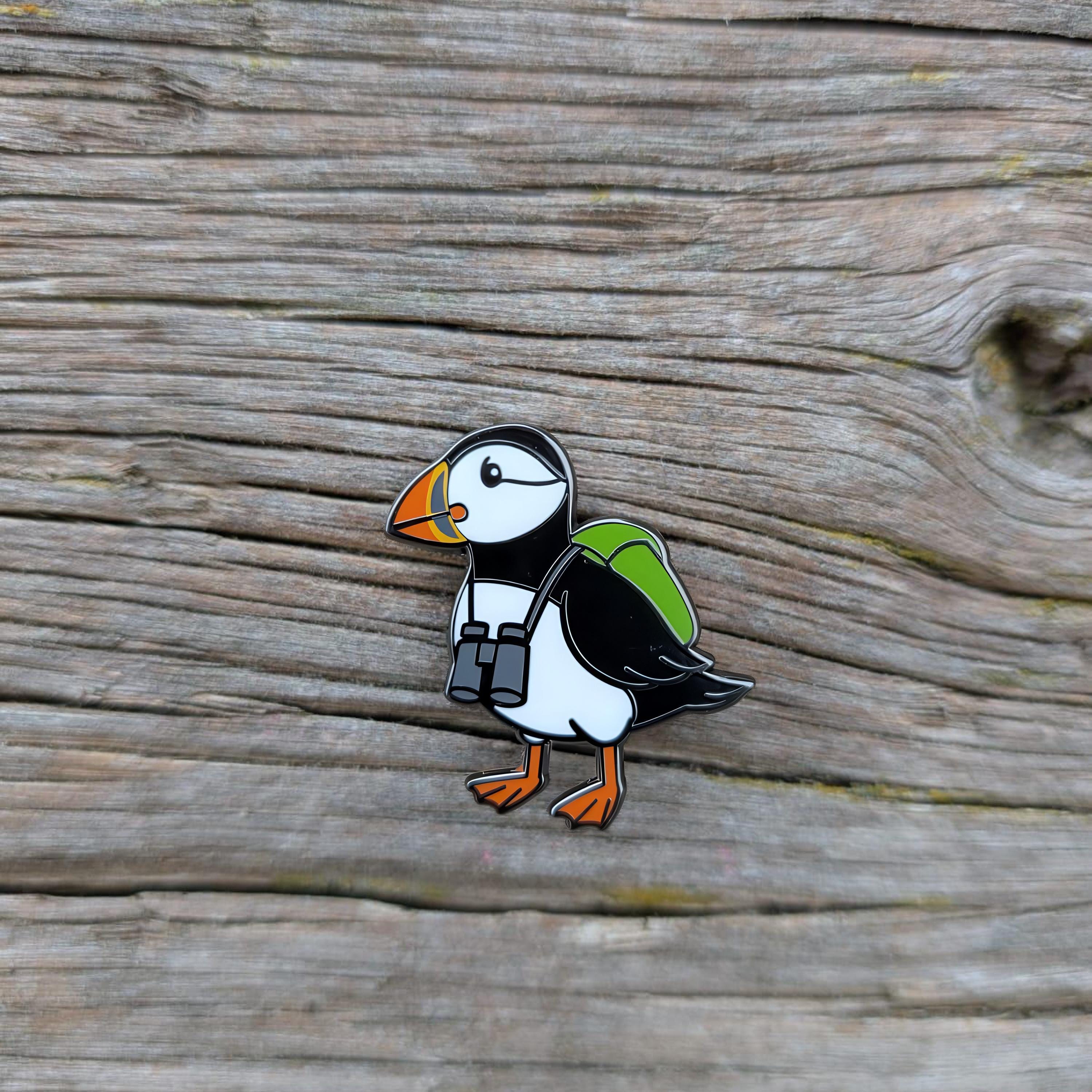 Puffin-shaped pin with a backpack on a wooden surface